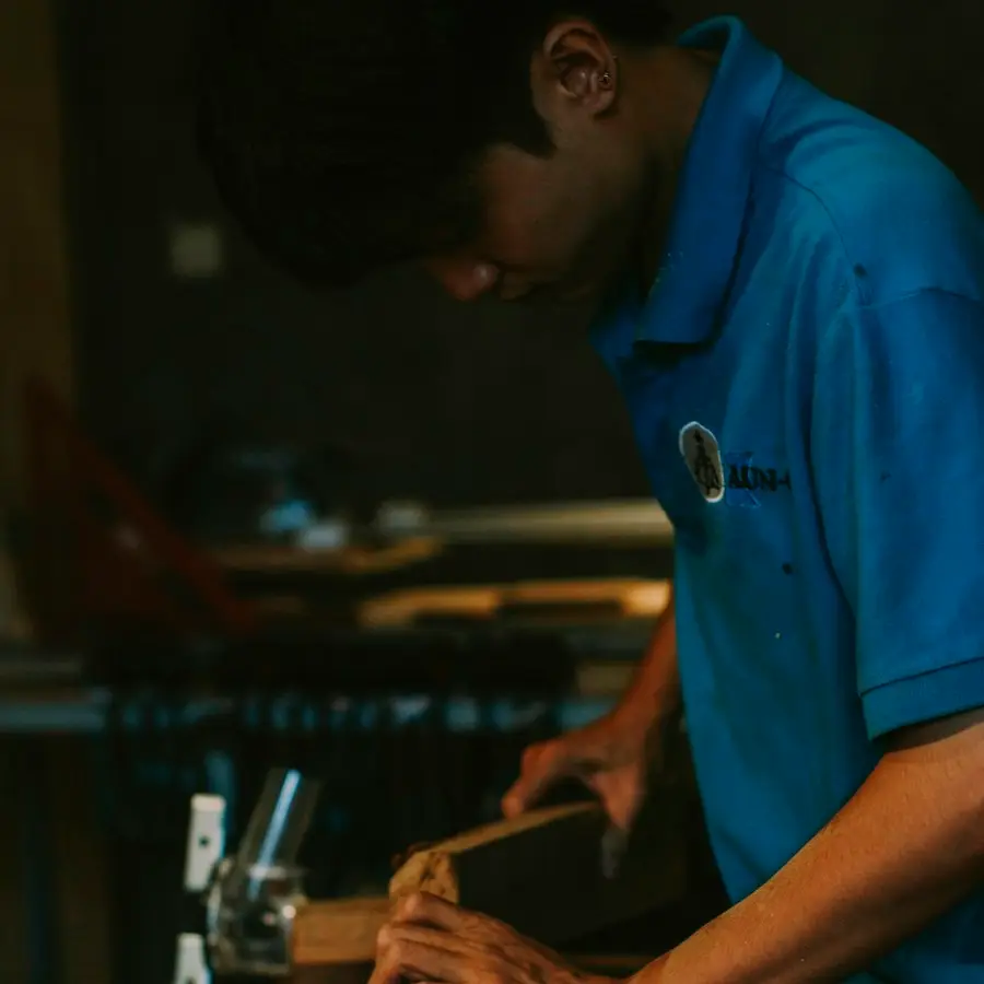 A carpenter shaping timber at a workbench