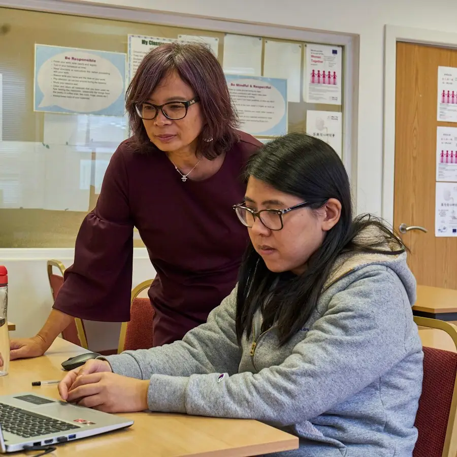 One person showing another something on a laptop screen