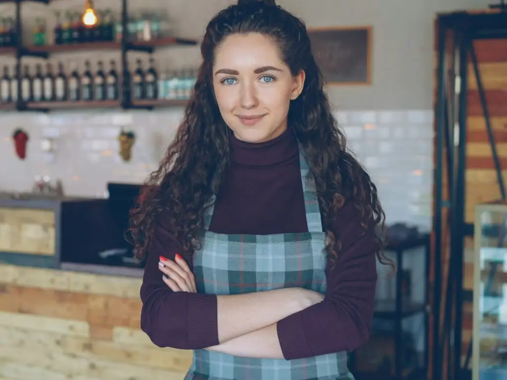 A business owner standing behind the counter of her coffee shop